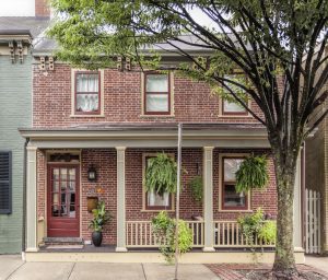 A generously-sized c.1850 brick row house with a narrow Colonial Revival porch located in the central business district.